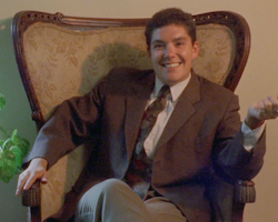 A person smiling and sitting in an armchair.