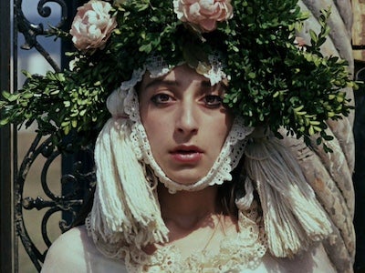 A woman wearing a garland of leaves and flowers on her head.