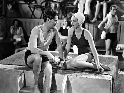 A man and a woman wearing swimsuits and sitting next to each other.