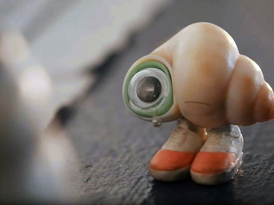 A seashell with one googly eye and a pair of shoes.