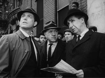 Three men talking in a city street.