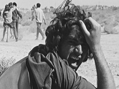 A person screaming and grabbing their hair on the side of a road.