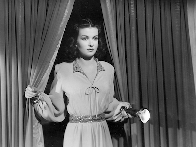 Joan Bennett holding a flashlight.