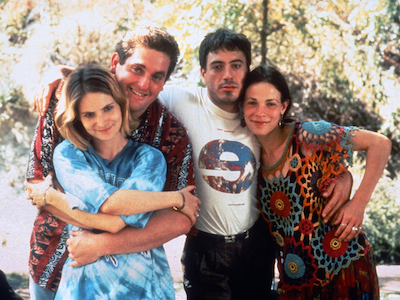 Four people smiling and standing with their arms wrapped around each other.