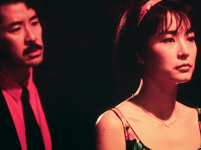 A man standing behind a woman at night.