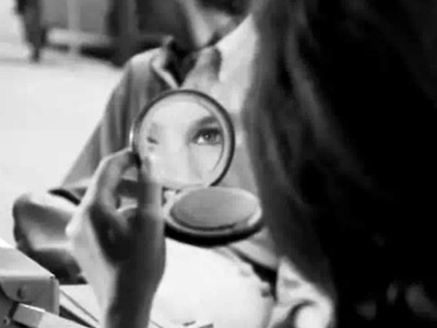 A woman looking into a compact mirror. 