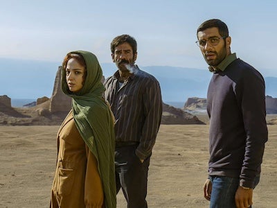 Three people standing in the desert.