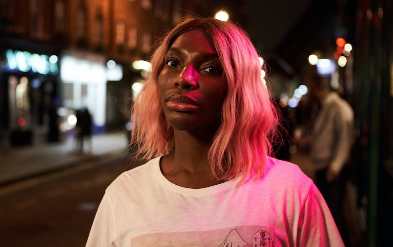 Michaela Coel standing outside at night.