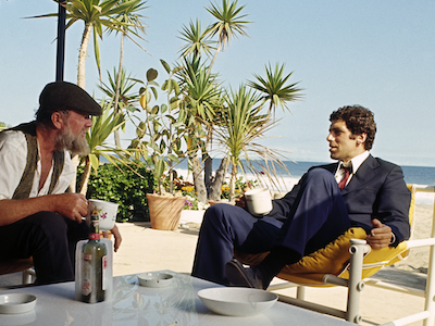 Elliott Gould sitting in a beach chair.