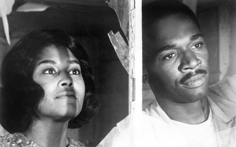 Abbey Lincoln and Ivan Dixon looking out a broken window.