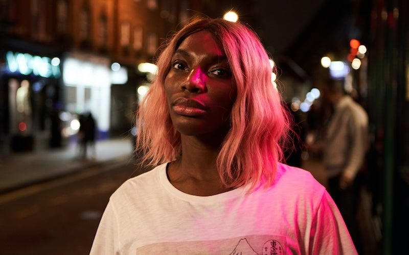 Michaela Coel standing outside at night.