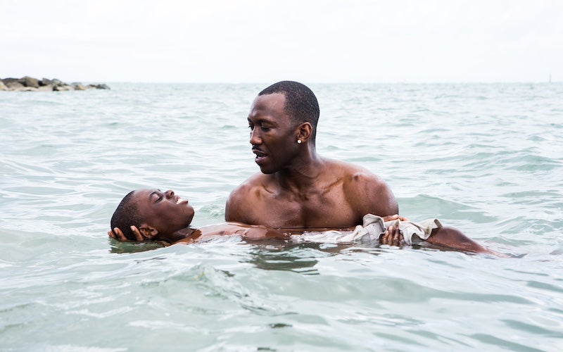 A man helping a young boy float in the ocean.