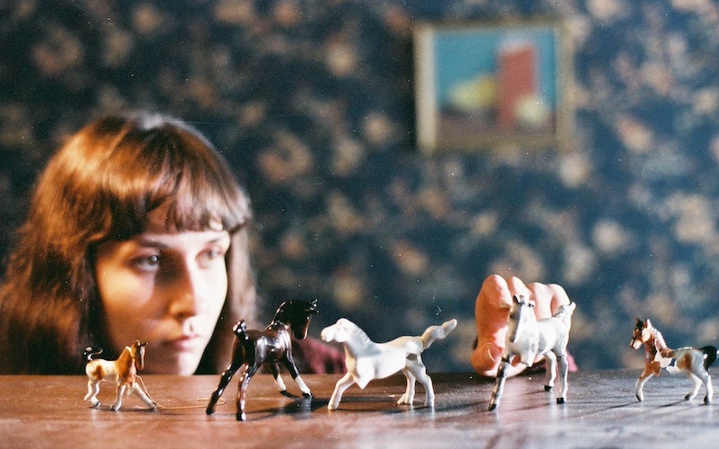A woman looking at small toy horses.