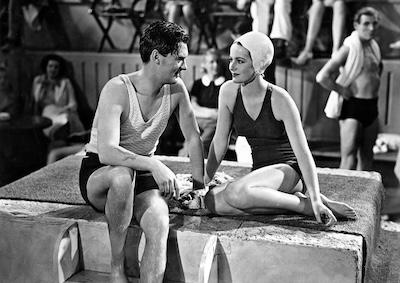 A man and a woman wearing swimsuits and sitting next to each other.