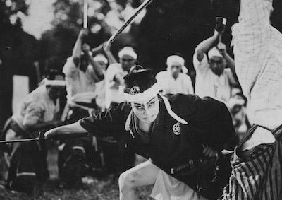 A man wielding a Japanese sword against a group of men.