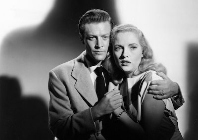 The Burning Cross A man embracing a frightened woman, a shadow looming behind them.