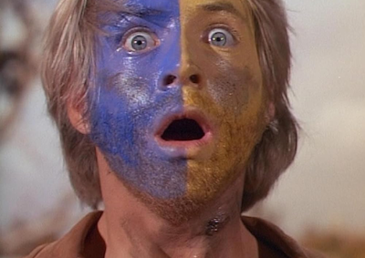 A stunned looking man with paint on his face.