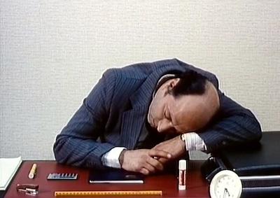 A man resting his head on a desk.