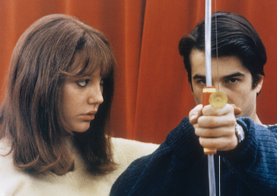 A woman looking at a man who is holding a bow and arrow.