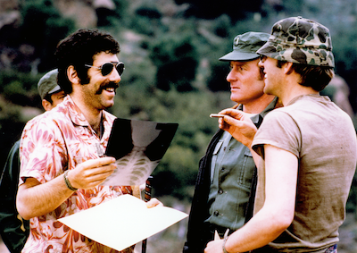 A man holding up an x-ray to two people in army attire.