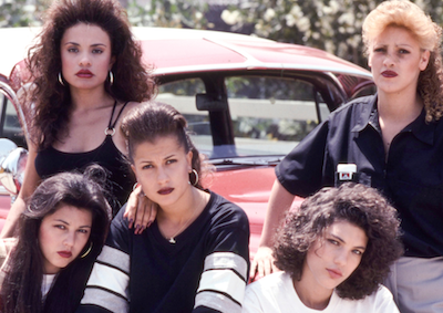 Five women posing in front of a car.