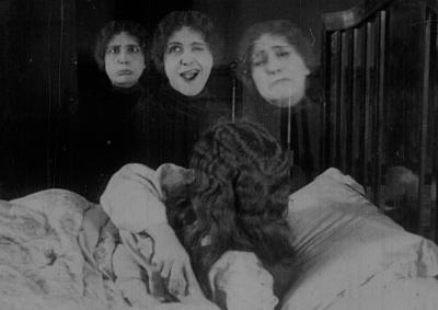 The image of three heads floating above a woman in bed.