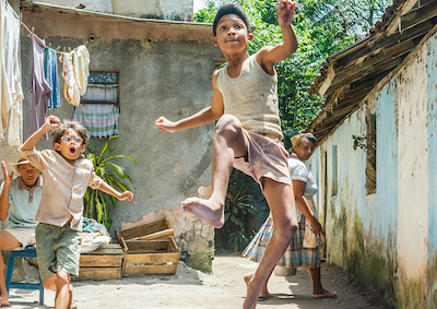 Two young boys running and leaping outdoors.