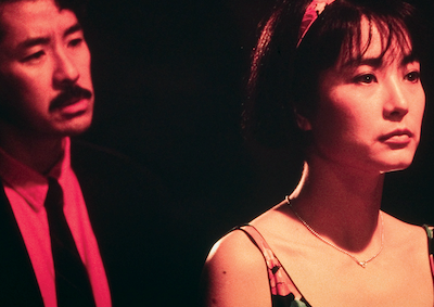 A man standing behind a woman at night.