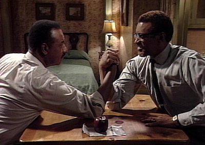 A fictional Martin Luther King Jr. and Malcolm X arm wrestling in a room. 