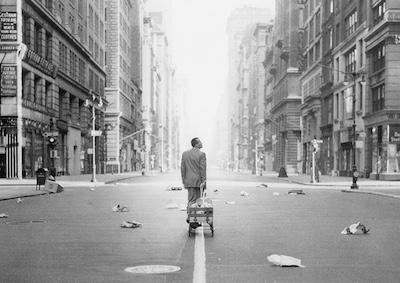 A man pulling a cart through an empty city.