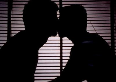 The silhouette of two men kissing.