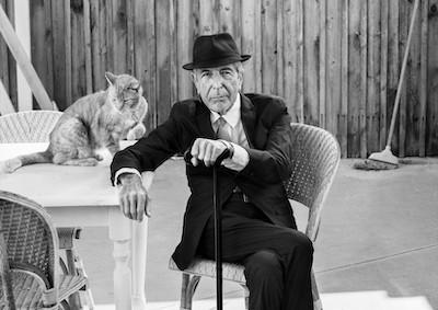 Leonard Cohen seated next to a cat.