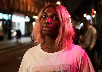 Michaela Coel standing outside at night.