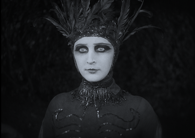 A person in a feathered costume and dramatic eye makeup.