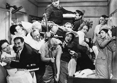 13 people piled on top of each other in a small room.