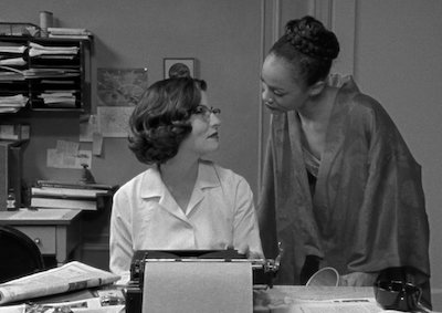 Two women gazing closely at each other in an office.