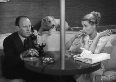 Actors Roland Young, Constance Bennett and Asta the dog sitting around a table.