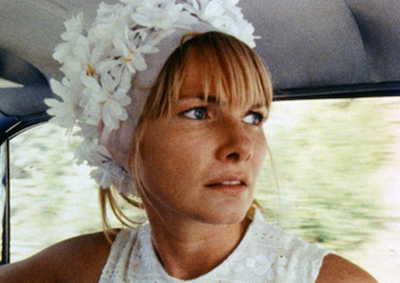 A woman wearing a flowery hat in a car.
