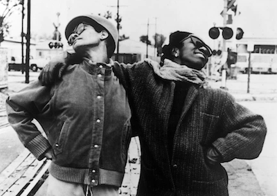 Two young women smiling with their arms over each other's shoulders.
