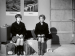 Two young women sitting on suitcases.