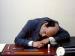 A man resting his head on a desk.