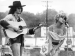 A woman singing into a microphone next to a man playing guitar.