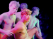 Four shirtless men posing under neon lights.