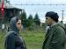 A woman and a man speaking by a barbed wire fence.