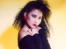 A young woman posing in 1980s hair and fashion.