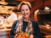 Alice Waters smiling and holding persimmons.